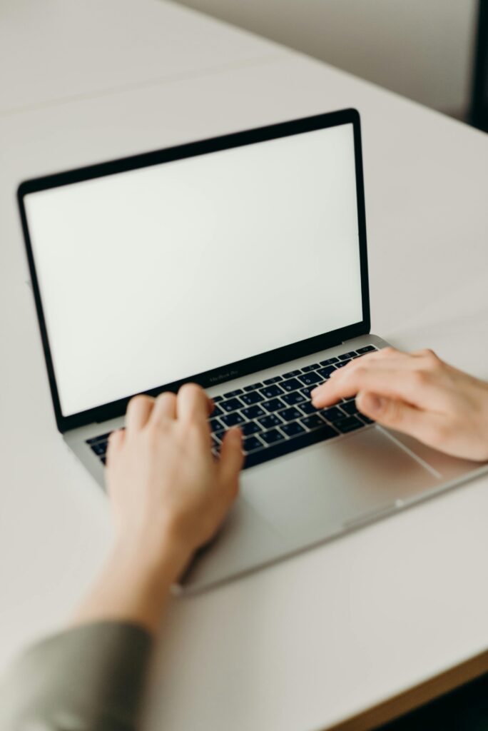 Close-up of hands typing on a laptop with a blank screen in a modern workspace.